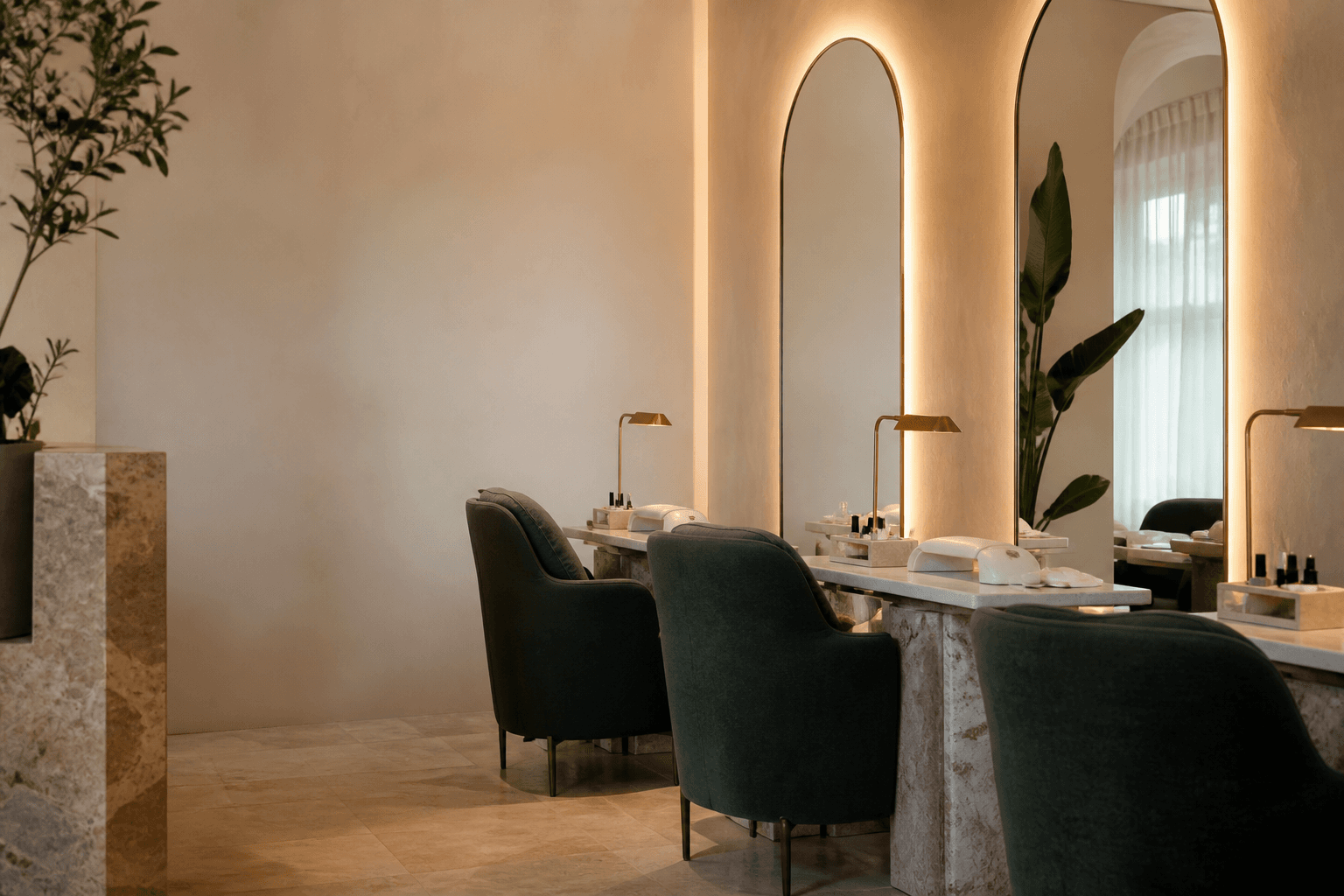 Warm boutique salon interior with forest green chairs, arched mirrors and brass lighting