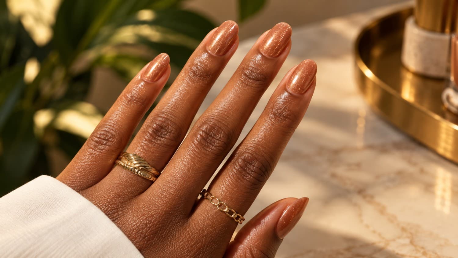 Natural human hands with a soft nude manicure resting on a warm stone table
